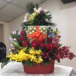 Mixed flowers and ferrero rocher chocolate in a red basket.
