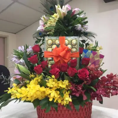 Mixed flowers and ferrero rocher chocolate in a red basket.