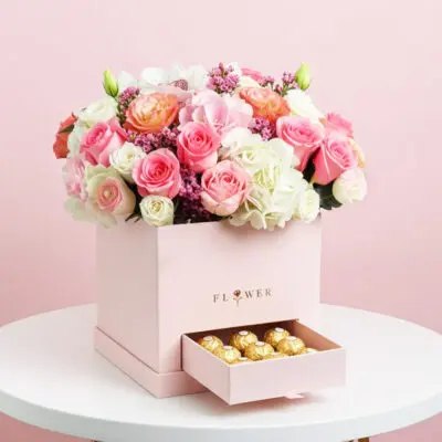 A pink box adorned with flowers and chocolates sits elegantly on a table.