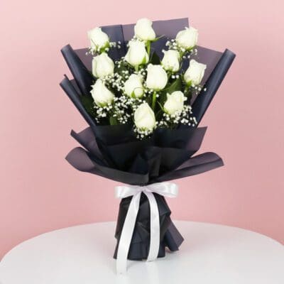 A bouquet of white roses elegantly tied with a black ribbon, showcasing a classic and sophisticated floral arrangement.