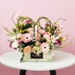 A basket filled with pink flowers placed on a wooden table, adding a touch of color to the setting.