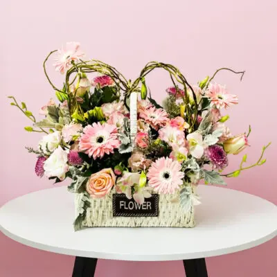 A basket filled with pink flowers placed on a wooden table, adding a touch of color to the setting.