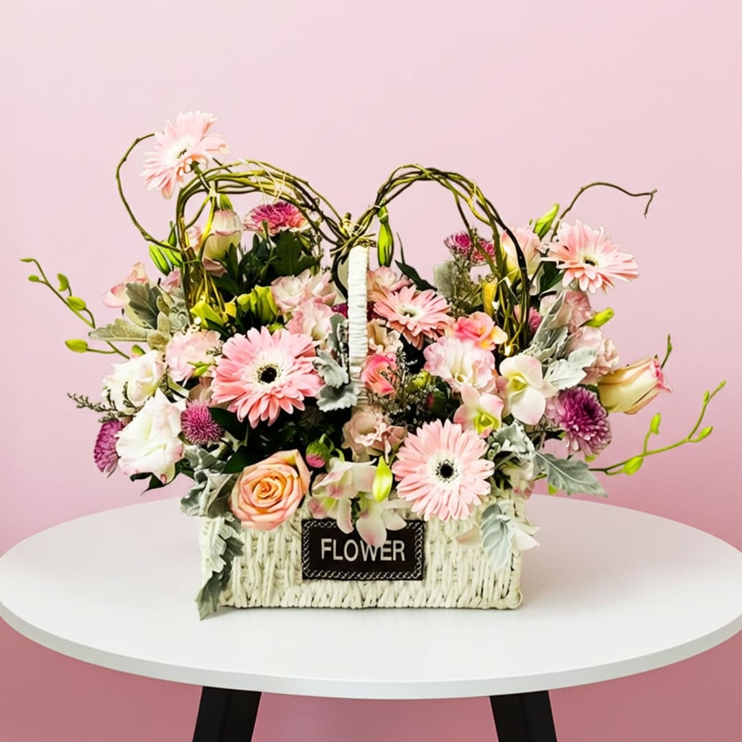 Lovely Pastel Flower Basket-01-12 A basket filled with pink flowers placed on a wooden table, adding a touch of color to the setting.