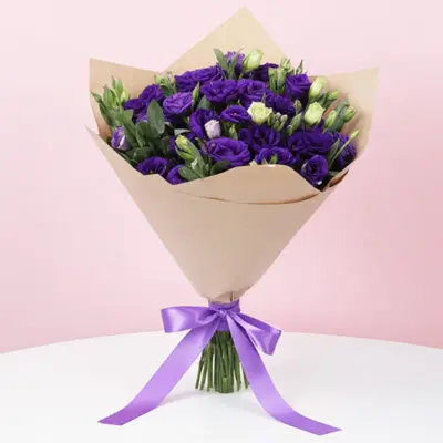 A vibrant purple bouquet featuring purple roses and lisianthus, complemented by lush green leaves.