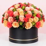 A large black box filled with vibrant orange and red roses, creating a striking floral display.