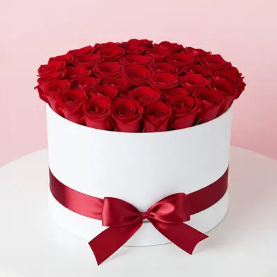 A white box adorned with vibrant red roses on top, creating an elegant floral display.