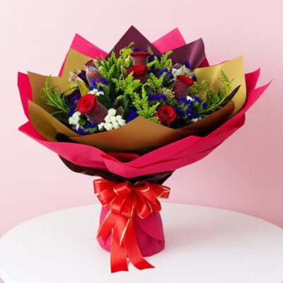 A bouquet featuring ten stems of red, blue, and purple roses, accented with lush green foliage.