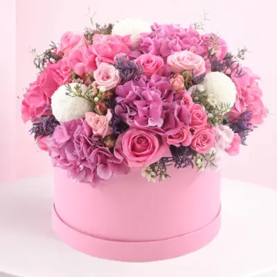 A pink box filled with an assortment of vibrant pink flowers, showcasing a lavish floral arrangement.