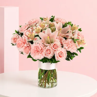 A floral arrangement featuring 110 pink roses, 10 pink carnations, 10 pink lilies, and 10 pink alstroemeria in a cylinder vase.