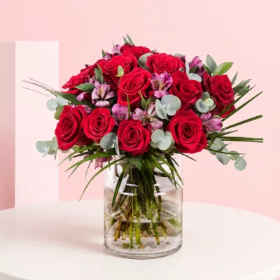 A vase filled with 15 red roses and 5 alstroemerias, showcasing a vibrant floral arrangement.