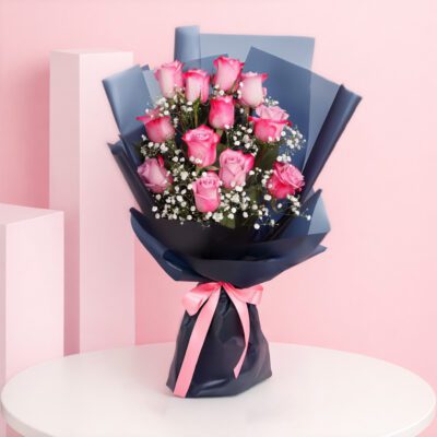 A bouquet of 12 pink roses surrounded by delicate baby's breath, elegantly arranged for a floral display.