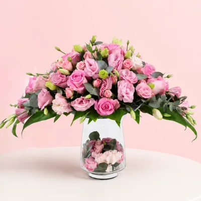 A lavish arrangement of pink roses in various shades, elegantly displayed in a decorative vase.