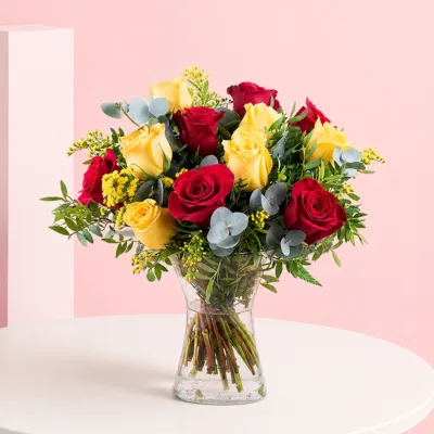 A cylinder vase filled with six yellow and six red roses, showcasing a vibrant floral arrangement.