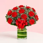 A bouquet of 12 red carnations in a chic cylinder vase, accompanied by a thoughtful message card expressing warmth and affection.