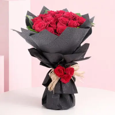 A vibrant bouquet of red roses arranged elegantly on a wooden table.