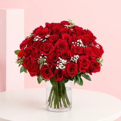 A bouquet of 35 red roses arranged in a clear cylinder vase, showcasing vibrant blooms and lush green leaves.