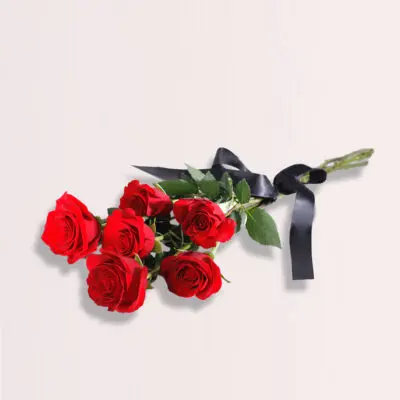 A hand-tied bouquet of six red rose stems elegantly wrapped with a black ribbon.
