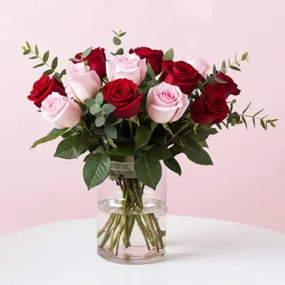 A vase filled with vibrant roses and lush greenery, showcasing a beautiful floral arrangement.