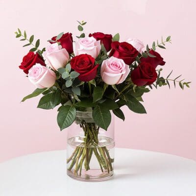 A vase filled with vibrant roses and lush greenery, showcasing a beautiful floral arrangement.