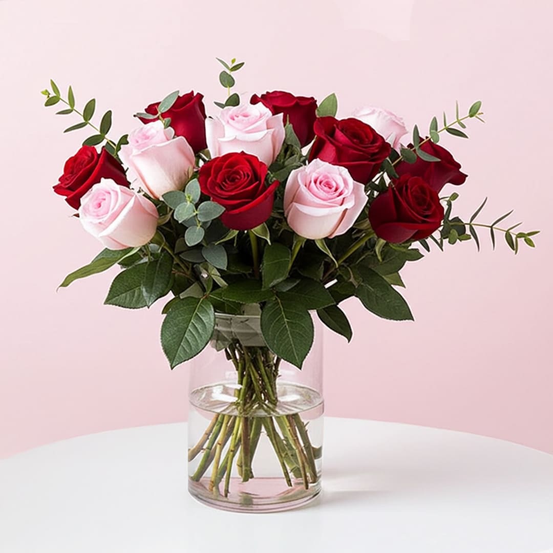 Peace of Red and Pink Roses-12 A vase filled with vibrant roses and lush greenery, showcasing a beautiful floral arrangement.