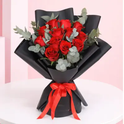 A romantic arrangement of a dozen red roses with eucalyptus leaves, ideal for expressing love on Valentine's Day.