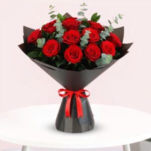 A bouquet of vibrant red roses tied with a matching red ribbon, elegantly arranged for a special occasion.