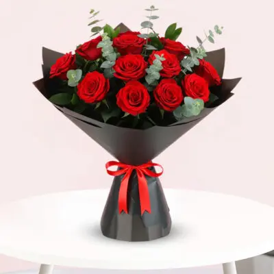 A bouquet of vibrant red roses tied with a matching red ribbon, elegantly arranged for a special occasion.