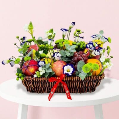 A woven basket filled with colorful fruit and vibrant flowers arranged together.