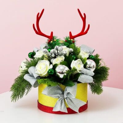 A holiday centerpiece with a bouquet of green leaves and deer antlers, arranged beautifully in a decorative box.