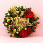 Christmas wreath with "Merry Christmas" text on a pink background, featuring festive decorations and greenery.