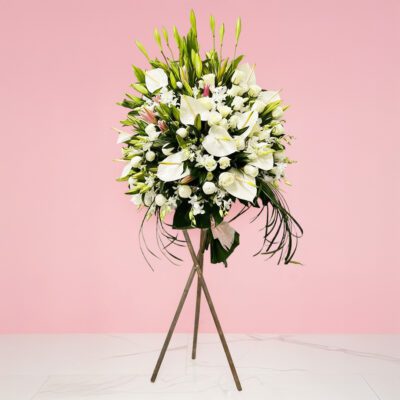 A white flower arrangement on a stand, symbolizing sympathy and associated with humility and goodness.
