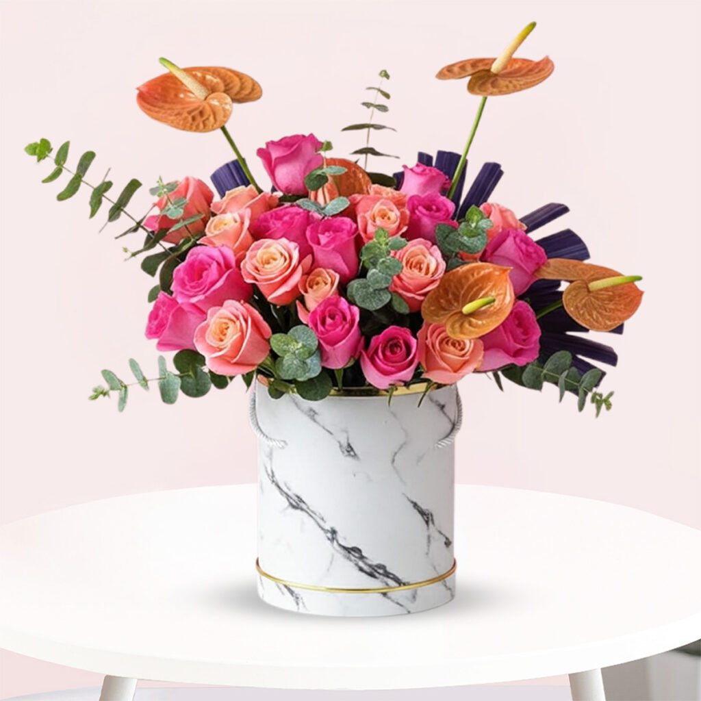 A bouquet of pink and orange roses arranged in a sleek marble vase.