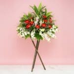 A flower arrangement titled 'Aspiration' displayed on a wooden stand, showcasing vibrant blooms and lush greenery.