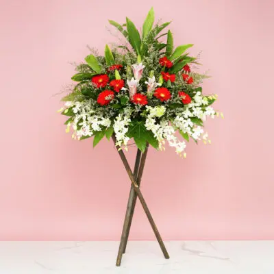 A flower arrangement titled 'Aspiration' displayed on a wooden stand, showcasing vibrant blooms and lush greenery.