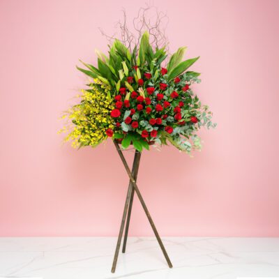 A Flower Arrangement On A Stand Featuring 40 Red Roses, 25 Yellow Golden Showers, And Seasonal Greenery.