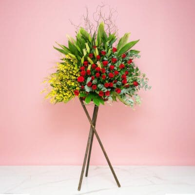 A Flower Arrangement On A Stand Featuring 40 Red Roses, 25 Yellow Golden Showers, And Seasonal Greenery.