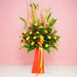 A Floral Arrangement Featuring Heliconia, Gerberas, And Roses Displayed On A Pink Background.