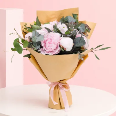 A vibrant pink peony in full bloom, showcasing its layered petals and lush green leaves in a natural setting.