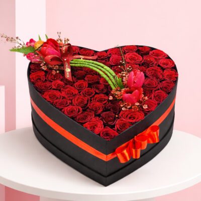 Heart-shaped box filled with vibrant red roses and tulips, symbolizing love and beauty.