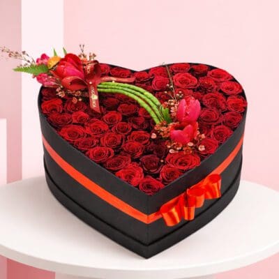 Heart-shaped box filled with vibrant red roses and tulips, symbolizing love and beauty.