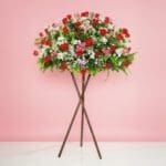 A Grand Opening Display Featuring A Large Arrangement Of Red Roses, Rose Sprays, And Seasonal Greenery On A Stand.