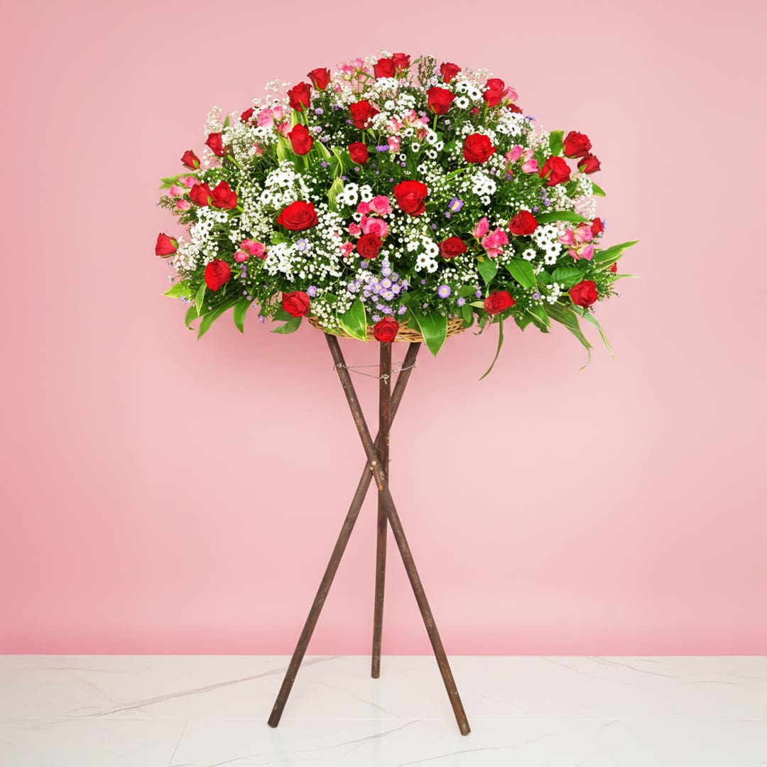 stunning-garden-25 A Grand Opening Display Featuring A Large Arrangement Of Red Roses, Rose Sprays, And Seasonal Greenery On A Stand.