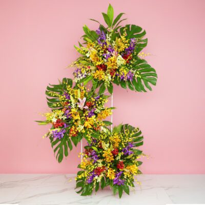 A Vibrant Flower Arrangement Featuring 90 Stems Of Mix Orchid And 10 Stems Of Casa Lily On A Soft Pink Background.