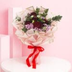 A bouquet of 13 vibrant red roses, elegantly arranged to create a stunning Crimson Blush display.
