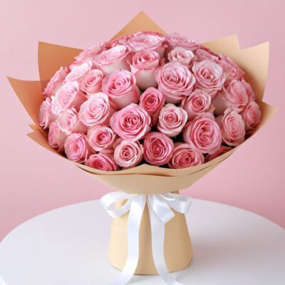 A bouquet of pink roses arranged elegantly on a white table, showcasing their vibrant color and delicate petals.
