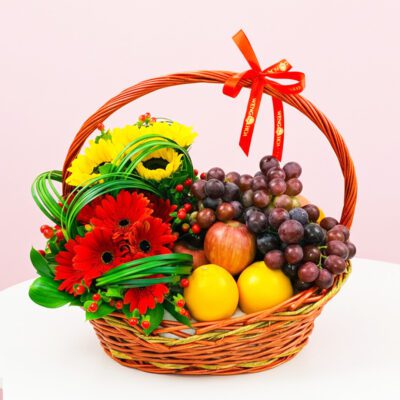 A woven basket filled with colorful fruit and vibrant flowers arranged together.