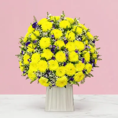A decorative stand containing a mix of yellow and purple sympathy flowers.