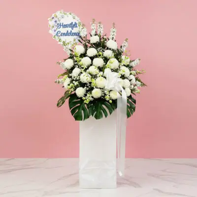 A white stand filled with white flowers with a Heartfelt Condolence sign.