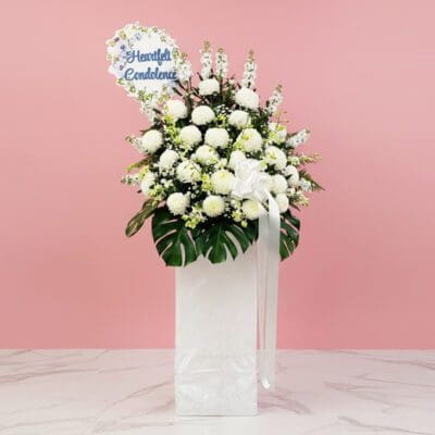 A white stand filled with white flowers with a Heartfelt Condolence sign.