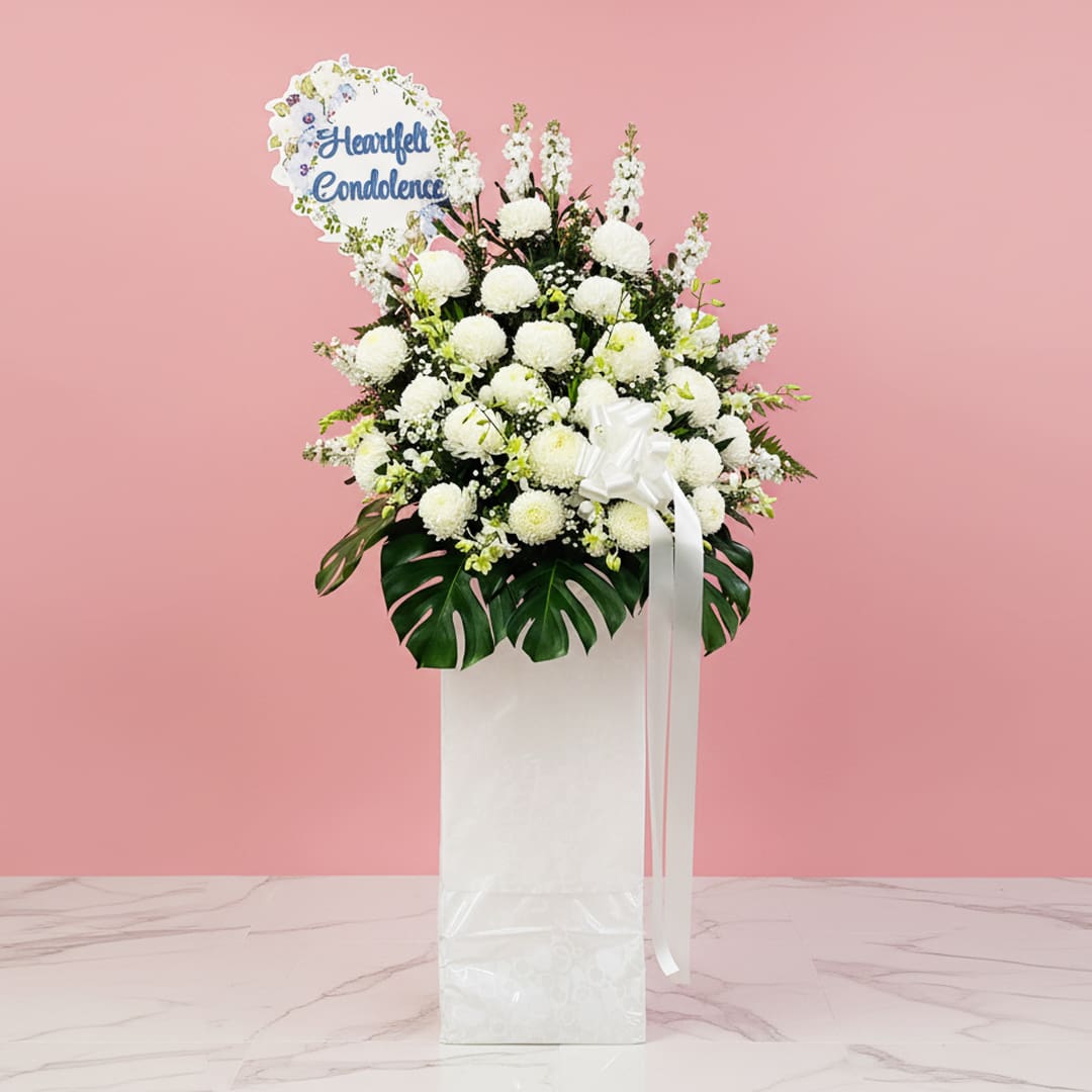 Healing Grace A white stand filled with white flowers with a Heartfelt Condolence sign.